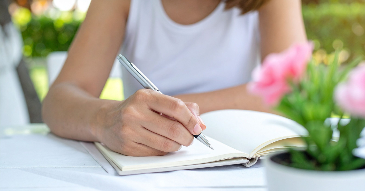 Woman journaling outdoors as part of a mindfulness practice