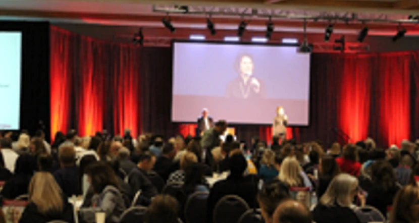 A diverse group of people engages at an event in a conference hall.